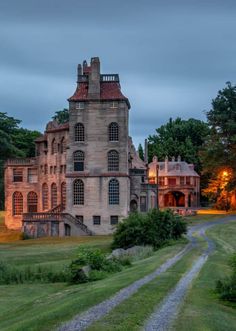 an old house is lit up at night in the distance, with a path leading to it