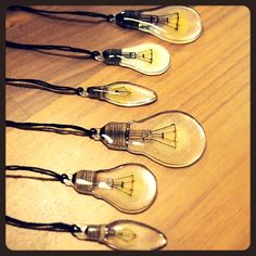 five light bulbs on a wooden table with black cord around the ends and one bulb is turned upside down