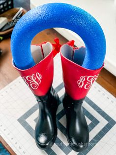 pair of rubber boots with monogrammed initials on them sitting on top of a table