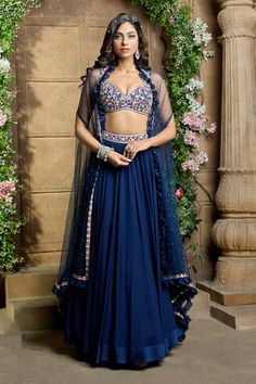 Navy cape with embroidered and ruffle border. Paired with thread embroidered padded bustier and gathered lehenga with attached cancan.
Components: 3
Pattern: Embroidery
Type Of Work: Thread
Neckline: Cape: Open, Blouse: V neck
Sleeve Type: Cape: Flared sleeves, Blouse: Sleeveless
Fabric: Lehenga: Chiffon, Bustier: Dupion, Dupatta: Butterfly Net
Color: Blue
Other Details: 
Lehenga Length: 45 inches
Ruffle bordered cape
Occasion: Destination Wedding - Aza Fashions Festive Lehenga With Cape, Festival Georgette Lehenga With Cape Sleeves, Fitted Lehenga With Cutdana And Cape Sleeves, Blue Lehenga With Cape Sleeves And Dupatta, Blue Sets With Sheer Dupatta And Cape Sleeves, Cape Lehenga, Blue Lehenga, Fashion App, Flared Sleeves