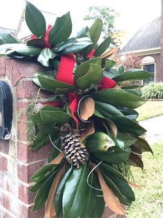 a christmas wreath is hanging on the side of a brick wall in front of a mailbox