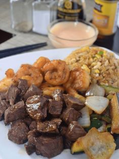 a white plate topped with meat and veggies covered in sauce next to beer bottles