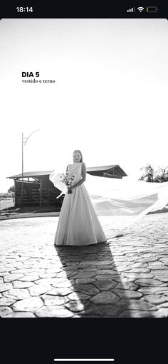 a black and white photo of a woman in a wedding dress standing on a cobblestone road