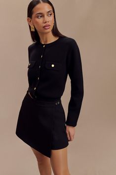 a woman in a black dress and gold buttons is posing for the camera with her hands on her hips