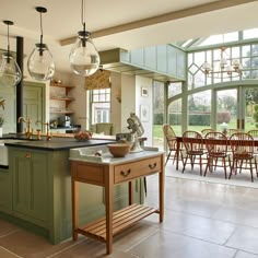 a kitchen with green cabinets and wooden chairs