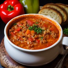 a white bowl filled with soup next to bread and peppers