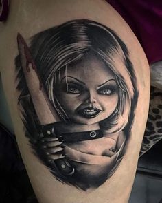 a woman holding a knife tattoo on her thigh