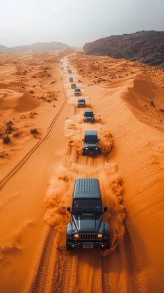 four jeeps driving through the desert on sand