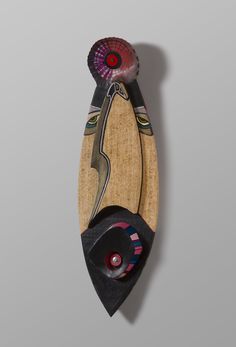 a wooden wall hanging with an abstract design on it's face and two red eyes