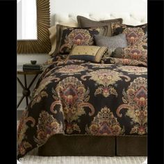 a bed with a black and gold comforter on top of it next to a mirror