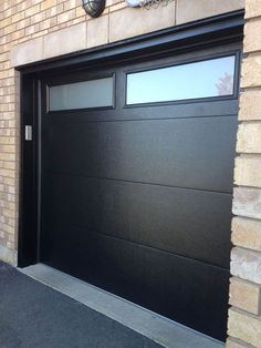 a black garage door is open on a brick building