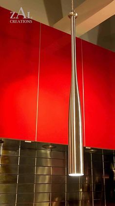 a modern light fixture hanging from the ceiling in a kitchen with red walls and tiled flooring