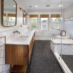 a bathroom with two sinks and a bathtub next to a large mirror on the wall