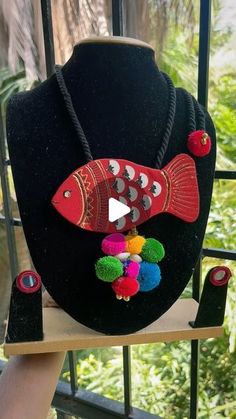 a black hat with red fish and pom - poms on it's side