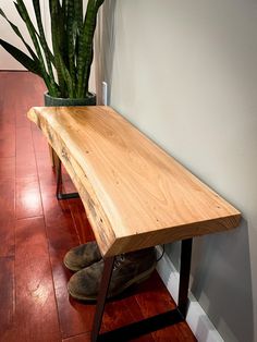 a wooden bench sitting on top of a hard wood floor next to a potted plant