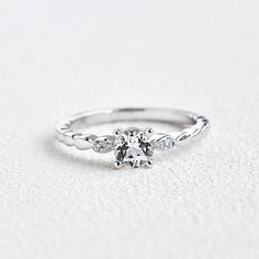 a white gold engagement ring with an oval center stone and three small diamonds on the band