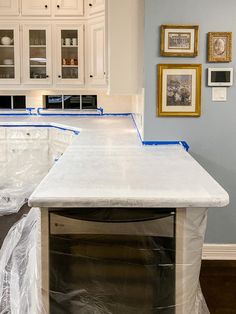 the kitchen counter is covered in plastic and ready to be painted white with blue tape