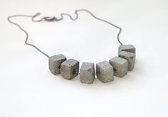 a necklace made out of concrete blocks on a white surface with a chain attached to it