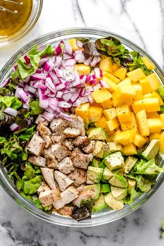 a salad with chicken, lettuce, red onion, and pineapple slices