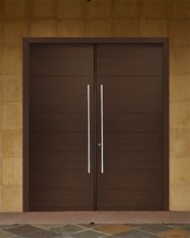 two brown double doors in front of a brick wall and stone floored patio area