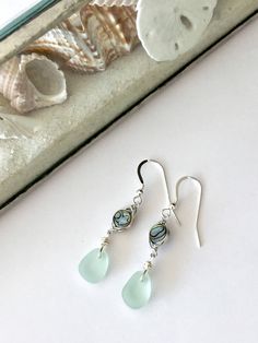 These elegant made to order seafoam sea glass and abalone shell drop earrings feature pieces of sea glass that are beautifully matched in shape, size, and color. A matching necklace can be purchased too either separately or as a set. Each piece is made using genuine sea glass that has been ocean-tumbled. For an idea of size please see photo 4. The necklace hangs on an 18 inch sterling silver chain. The abalone shell is wire wrapped. The ear wires are sterling silver. These sea glass jewelry will Elegant Teardrop Beach Jewelry, Elegant Teardrop Jewelry For Beach, Elegant Sea Glass Jewelry With Ear Wire, Elegant Jewelry With Sea Glass And Ear Wire, Elegant Blue Sea Glass Jewelry, Sea Glass Teardrop Earrings For Beach, Sea Glass Teardrop Earrings As Gift, Teardrop Sea Glass Earrings For Gift, Nickel-free Teardrop Jewelry For Beach