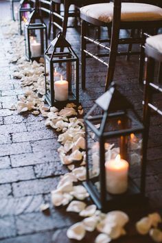 candles are lined up on the ground with petals and shells all over it, along with other lanterns