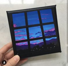 a hand holding up a small window with blue and pink clouds