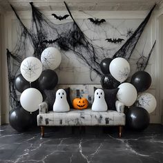 a couch with halloween decorations and balloons in front of a wall decorated with black and white spider webs