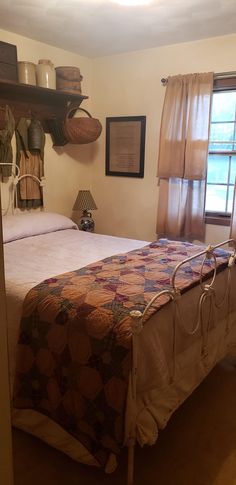 a bed sitting in a bedroom under a window next to a shelf with baskets on it