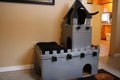 a cat house made out of cardboard with a black cat sitting on top of it