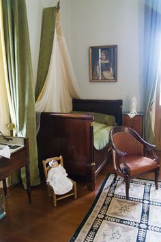 a bedroom with a bed, desk and chair in it's corner next to a painting on the wall