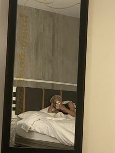 a person taking a selfie in front of a mirror on the wall next to a bed