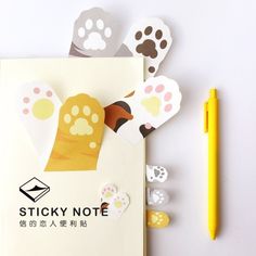 a notepad with paper cut out of it next to a pencil and some animal paw prints