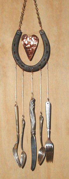 an assortment of utensils hanging from a chain with a heart shaped decoration on it