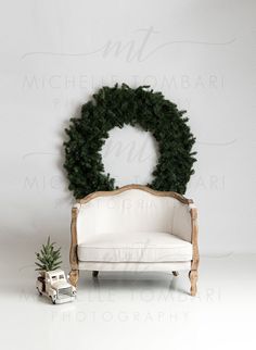 a white couch sitting in front of a christmas wreath on top of a wooden frame