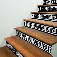 a set of wooden stairs with black and white designs on the riser treads