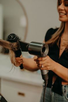 a woman blow drying her hair with a dryer