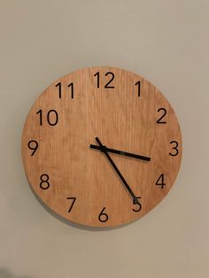 a wooden clock with black numbers on the face