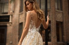 a woman in a wedding dress standing next to a lamp post with her back turned towards the camera