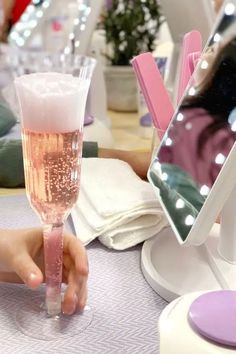 a person holding a wine glass in front of a mirror on a table with other items