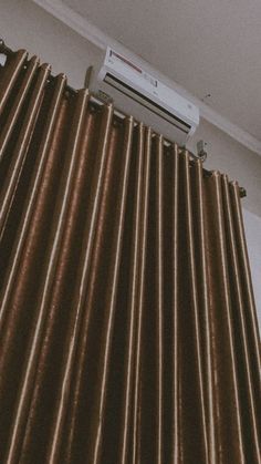 an air conditioner sitting on top of a brown curtain