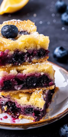 blueberry cheesecake bars stacked on top of each other with berries and powdered sugar