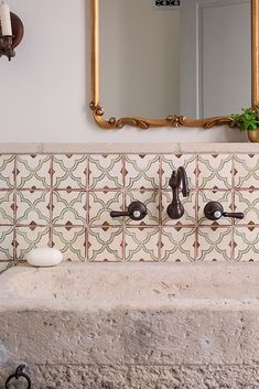 a bathroom sink sitting under a large mirror next to a wall mounted faucet