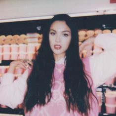 a woman standing in front of a shelf with donuts and other items on it