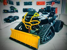 a large yellow snow plow sitting on top of a white floor next to a wall