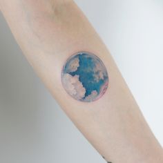 a person's arm with a blue and white moon tattoo on it