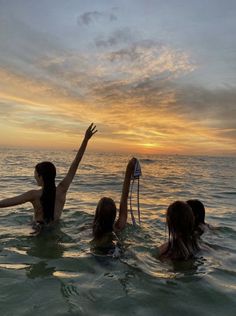 three women in the water with their arms up