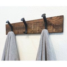 the towel hooks are made from wood and have black iron brackets on them, along with two gray towels