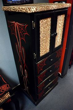 a black and red cabinet with spider webs on it's doors is next to a television