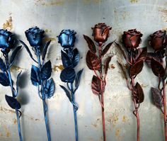 four metal roses are lined up against a wall